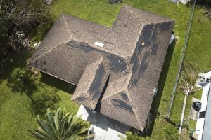 Wind damaged house roof with missing asphalt shingles